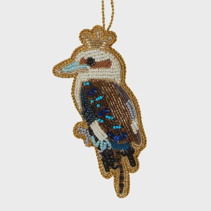 A sequin decoration shaped like a bird, predominantly blue and gold in color, with a crown on its head and sequin patterns on its body.