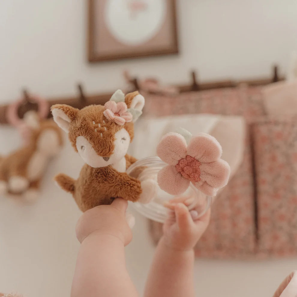 Plush deer toy with a teething ring and pink flower on a light gray background