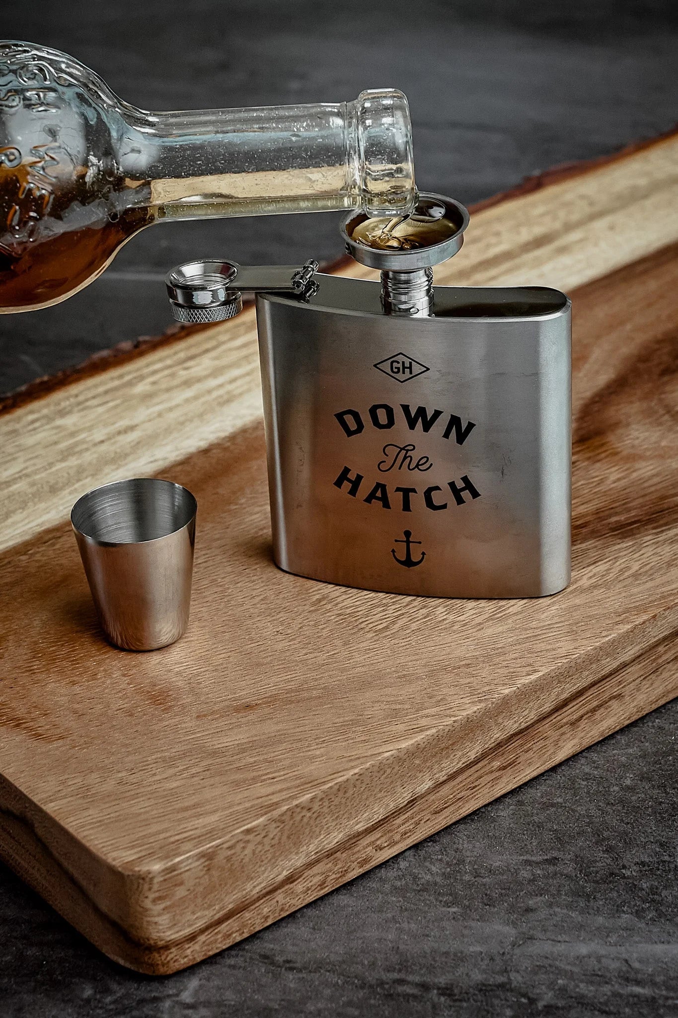 Stainless steel flask with 'Down The Hatch' engraving on a wooden surface.