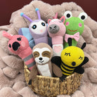 colorful knitted baby rattles/toys in a basket on a soft fabric background.  toys are hand knitted.