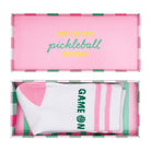 Pink and green pickleball-themed packaging with GAME ON socks inside
