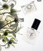 Two perfume bottles with a floral arrangement on a white background