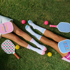 Two people lying on grass with colorful paddle ball games and socks.