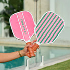 Two colorful paddle sports with striped designs held by a person outdoors.